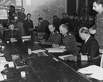 Generaloberst Alfred Jodl ondertekent de onvoorwaardelijke capitulatie van de Duitse strijdkrachten in Reims, 7 mei 1945.
Links: majoor W. Oxenius (tolk); rechts Generaladmiral H-G von Friedeburg.